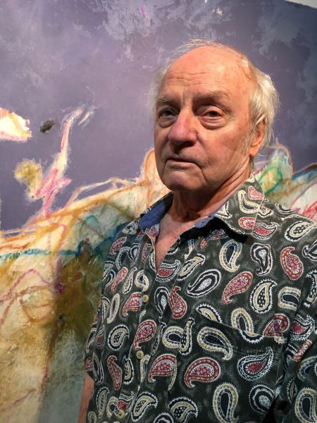 The artists Otis Huband standing in front of one of his paintings.
