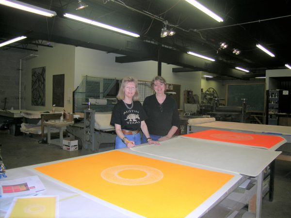 An image of the press room with two people sending behind a table proofing prints