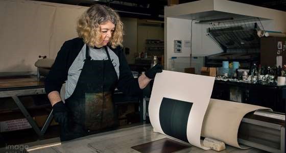 Katherine examining a proof print as it is being pulled off the plate.